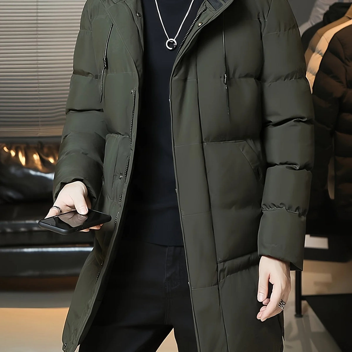 Men's green hooded longline puffer coat, front view with hand in pocket